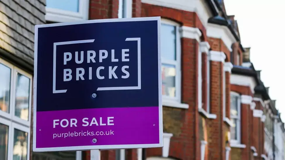 Purplebricks for sale sign in front of a row of terrace houses